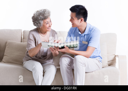 Soins infirmiers et travailleur masculin senior woman looking at photo album Banque D'Images