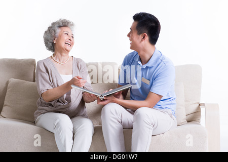 Soins infirmiers et travailleur masculin senior woman looking at photo album Banque D'Images