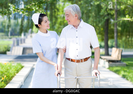 Man Walking avec déambulateur sous l'assistance de l'infirmière Banque D'Images