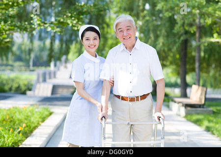 Man Walking avec déambulateur sous l'assistance de l'infirmière Banque D'Images