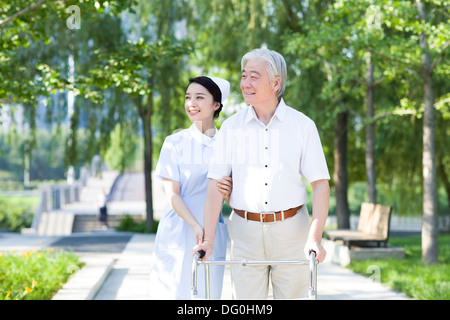 Man Walking avec déambulateur sous l'assistance de l'infirmière Banque D'Images