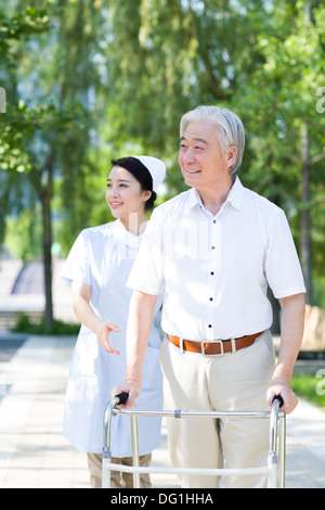 Man Walking avec déambulateur sous l'assistance de l'infirmière Banque D'Images