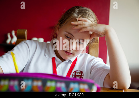 Douze ans caucasien fille en uniforme d'école faire leurs devoirs Banque D'Images