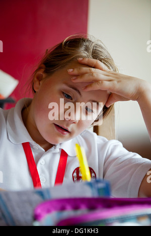 Douze ans caucasien fille en uniforme d'école faire leurs devoirs Banque D'Images