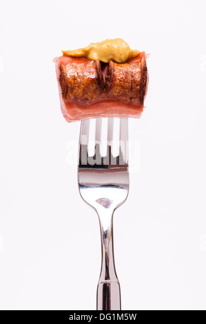 La moutarde sur une saucisse polonaise fumé sur une fourchette Banque D'Images