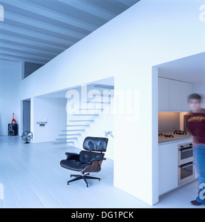 Soft focus figure debout dans la cuisine de grand appartement avec Charles Eames chaise de salon en cuir noir Banque D'Images
