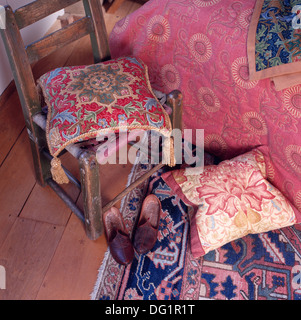 Des coussins colorés sur la vieille chaise en bois à côté de lit avec couette rose en rétro chambre avec carrelage sur tapis d'Orient Banque D'Images