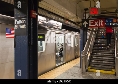 Un train de métro de New York attend brièvement à Fulton Street dans le quartier financier. Quelques passagers sont entrés ou sortis. Banque D'Images