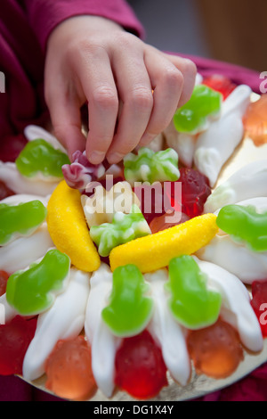 Close up de la main d'un enfant, prise d'une gomme douce parmi une vaste sélection de bonbons colorés. Banque D'Images