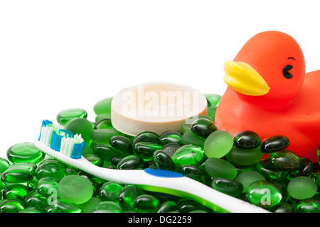 Brosse à dents, savon et rubber duck toy niché parmi les perles de verre vert sur fond blanc. Parfait pour une disposition en coin. Banque D'Images