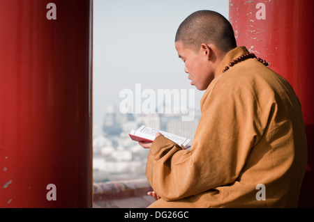 Jeune moine priant dans pavillon Wanchun ting (Pavillon de printemps) dans le parc Jingshan, Beijing, Chine Banque D'Images