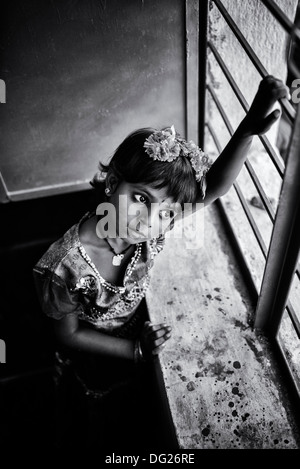 Jeune indienne debout à la fenêtre de la salle de l'école un jour rêver de l'Andhra Pradesh, Inde. Noir et blanc. Banque D'Images