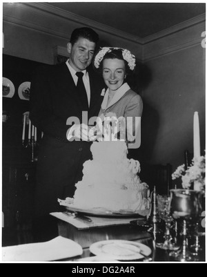 Cette photographie montre Ronald et Nancy Reagan, jeunes mariés, coupant leur gâteau de mariage dans un moment de célébration. L'image marque un jalon personnel important pour le couple en 1952, avant la carrière politique de Reagan. Banque D'Images