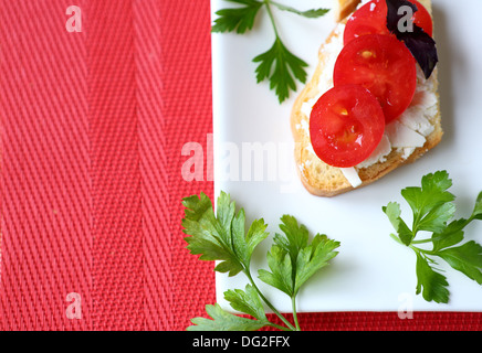 Croustillant de pain grillé avec du fromage et des tomates sur une assiette blanche, de l'alimentation Banque D'Images