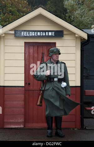 Guerre 1940 Sentinelle. Un homme dans l'armée reenactor tin hat à Levisham. North Yorkshire, UK. 11 octobre, 2013. Le Feldgendarmerie au chemin de fer en temps de guerre' 'North York Moors Railway (NYMR) Événement à Levisham gare dans le mauvais temps le week-end 12th-13th Octobre 2013. La station de Levisham, a été décoré avec des affiches, et des signes française pendant la guerre (NYMR) 'Week-end' de devenir 'le' Visham dans le nord de la France. Le rassemblement, une reconstitution d'un village occupé par la Seconde Guerre mondiale, la seconde guerre mondiale, la seconde guerre mondiale, LA DEUXIÈME GUERRE MONDIALE, les troupes allemandes, WW2 Banque D'Images