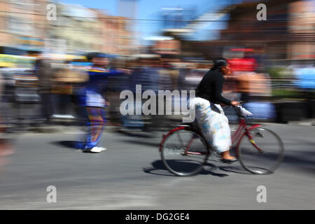 El Alto, Bolivie. 12 octobre 2013. Une concurrente passe devant les spectateurs alors qu'elle participe à une course de vélos Cholitas pour les femmes indigènes Aymara. La course se déroule à une altitude d'un peu plus de 4 000 m le long des routes principales de la ville d'El Alto (au-dessus de la Paz) pour la Journée des femmes boliviennes, qui était hier vendredi 11 octobre. Crédit : James Brunker / Alamy Live News Banque D'Images