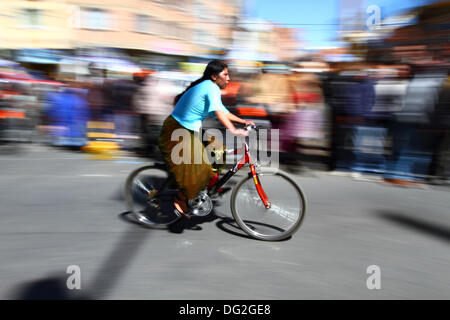 El Alto, en Bolivie. 12 octobre, 2013. Un coureur monte comme spectateurs passé elle prend part à une course cycliste pour les Cholitas Aymaras des femmes. La course a lieu à une altitude d'un peu plus de 4 000 m le long des principales routes de la ville de El Alto (au-dessus de la capitale, La Paz) pour la Journée des femmes boliviennes, qui était hier vendredi 11 octobre. Credit : James Brunker / Alamy Live News Banque D'Images