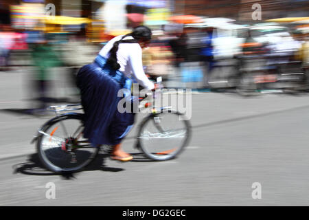 El Alto, en Bolivie. 12 octobre, 2013. Un coureur monte comme spectateurs passé elle prend part à une course cycliste pour les Cholitas Aymaras des femmes. La course a lieu à une altitude d'un peu plus de 4 000 m le long des principales routes de la ville de El Alto (au-dessus de la capitale, La Paz) pour la Journée des femmes boliviennes, qui était hier vendredi 11 octobre. Credit : James Brunker / Alamy Live News Banque D'Images