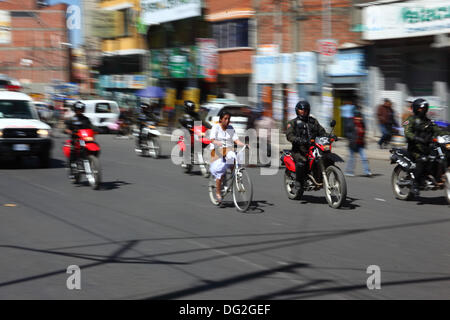 El Alto, Bolivie. 12 octobre 2013. L'une des dernières compétitrices passe avec une escorte de police (pour contrôler la circulation) alors qu'elle termine une course de vélos Cholitas pour les femmes indigènes Aymara. La course se déroule à une altitude d'un peu plus de 4 000 m le long des routes principales de la ville d'El Alto (au-dessus de la Paz) pour la Journée des femmes boliviennes, qui était hier vendredi 11 octobre. Crédit : James Brunker / Alamy Live News Banque D'Images