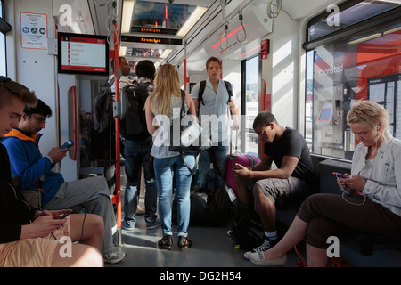 Les passagers utilisant des téléphones intelligents et des iPods dans un chariot élévateur sur le Bergen Light rail transit system local en Norvège Banque D'Images