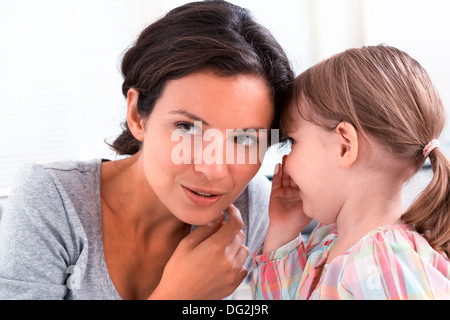 Mère heureuse avec sa fille dire un secret dans les portes Banque D'Images