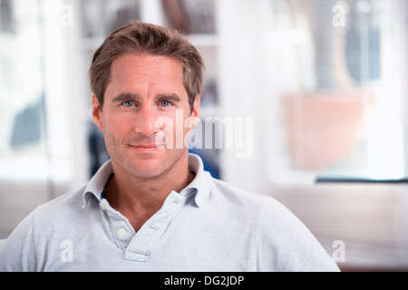 Homme assis sur le canapé de détente à la maison à la caméra à Smiling Banque D'Images