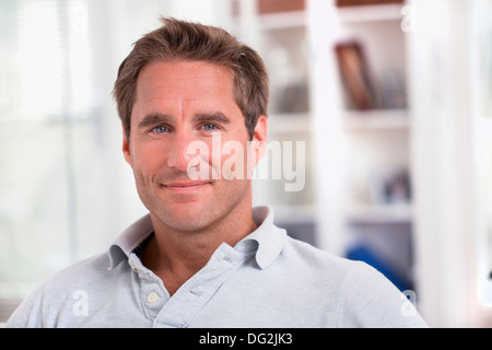 Homme assis sur le canapé de détente à la maison à la caméra à Smiling Banque D'Images