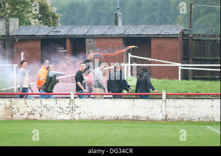 Atherstone, Warwickshire, Royaume-Uni. 12 octobre, 2013. Un groupe de fans à partir de l'extrémité de la route sol Sheepy marcher autour du périmètre de la hauteur et de l'échelle les clôtures pour attaquer le supporters visiteurs (Barrow AFC). Un feu d'artifice a également été lancée en direction de la terrasse de la voiture qui suit. Un drapeau a été volé de la Barrow AFC fans et ensuite mis le feu à l'aide d'un artifice allumé. Atherstone Président Rob Weale a présenté ses excuses pour ce qui s'est produit et a juré de poursuivre les auteurs. Banque D'Images