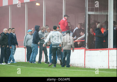 Atherstone, Warwickshire, Royaume-Uni. 12 octobre, 2013. Un groupe de fans à partir de l'extrémité de la route sol Sheepy marcher autour du périmètre de la hauteur et de l'échelle les clôtures pour attaquer le supporters visiteurs (Barrow AFC). Un feu d'artifice a également été lancée en direction de la terrasse de la voiture qui suit. Un drapeau a été volé de la Barrow AFC fans et ensuite mis le feu à l'aide d'un artifice allumé. Atherstone Président Rob Weale a présenté ses excuses pour ce qui s'est produit et a juré de poursuivre les auteurs. Banque D'Images