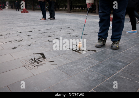 L'homme pratiquant la calligraphie chinoise en utilisant le pinceau et l'eau dans le Temple du Ciel, Beijing, Chine Banque D'Images