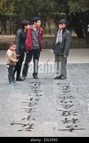 L'homme pratiquant la calligraphie chinoise en utilisant le pinceau et l'eau dans le Temple du Ciel, Beijing, Chine Banque D'Images