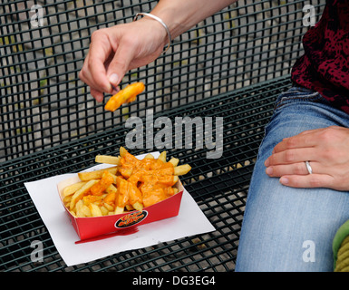Manger des frites avec de la mayonnaise belge sur un siège public Banque D'Images
