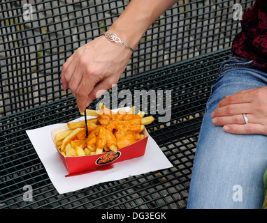 Manger des frites avec de la mayonnaise belge sur un siège public Banque D'Images