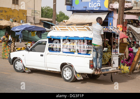 Sénégal, Touba. Le transport local. Pick-ups avec des jeunes hommes habituellement accroché sur le marchepied arrière, les passagers à l'intérieur. Banque D'Images