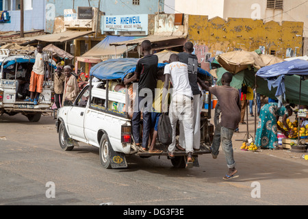 Sénégal, Touba. Le transport local. Pick-ups avec des jeunes hommes habituellement accroché sur le marchepied arrière, les passagers à l'intérieur. Banque D'Images