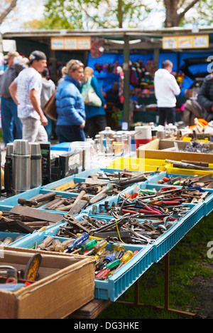 Les gens se promènent dans stands vendant divers outils d'occasion utilisés, l'équipement ménager et de bric-à-brac à un marché en plein air. Banque D'Images