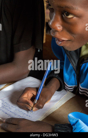 Sénégal, Touba. Garçon à la madrasa al-Azhar, une école pour les études islamiques, l'écriture en arabe dans son carnet. Banque D'Images