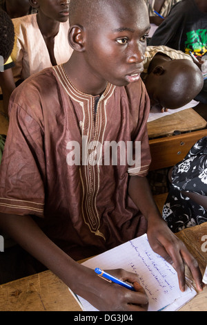 Sénégal, Touba. Garçon à la madrasa al-Azhar, une école pour les études islamiques, l'écriture en arabe dans son carnet. Banque D'Images