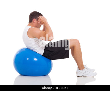 Jeune homme de faire les exercices de fitness sur ballon de gymnastique isolated on white Banque D'Images