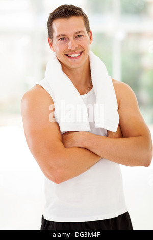 Jeune homme souriant à la gym avec les bras croisés après l'exercice Banque D'Images