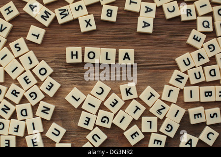 Lettres en plastique à partir d'une orthographe pour enfants jeu sur une table de bois sort 'hola' Banque D'Images