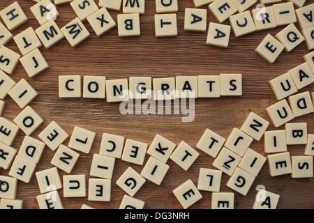 Lettres en plastique à partir d'une orthographe pour enfants jeu sur une table de bois sort 'félicitations' Banque D'Images