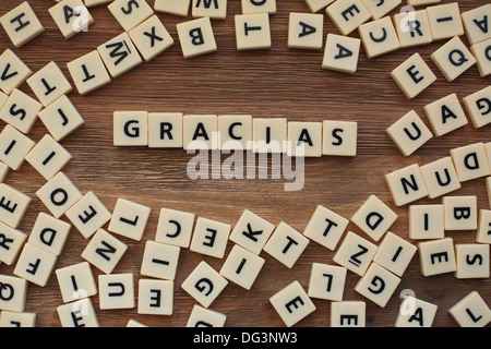 Lettres en plastique à partir d'une orthographe pour enfants jeu sur une table de bois sort "Gracias" Banque D'Images