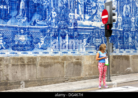 Jeune femme en face de l'azulejo carrelage mural bleu couvrant de Capela das Almas, du centre-ville, Porto, Portugal Banque D'Images