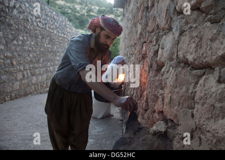 Lalish Yazidis, ville sainte dans le Nord de l'Iraq - saint homme allumage de la bougie d'huile rituelle dans le 365 lieu sacré dans la ville Banque D'Images