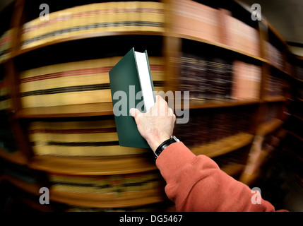 Main tenant livre dans une vieille bibliothèque en arrière-plan Banque D'Images