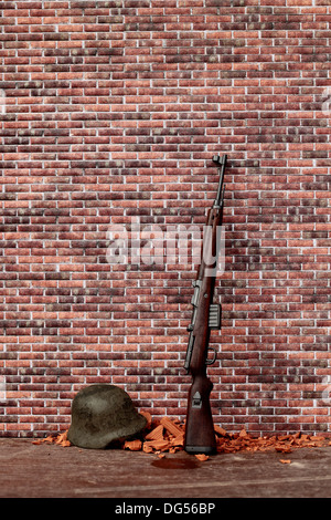 Casque et fusil sur un mur de briques Banque D'Images