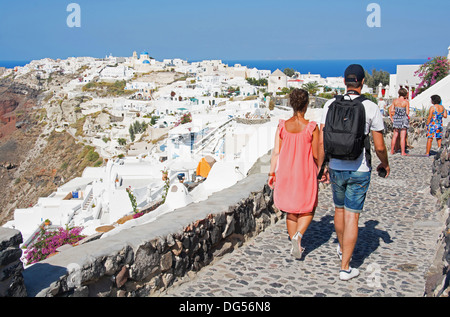 Santorin (thira), CYCLADES, en Grèce. Un couple en train de marcher le long d'une ruelle pavée dans le pittoresque village de falaise d'Oia. L'année 2013. Banque D'Images