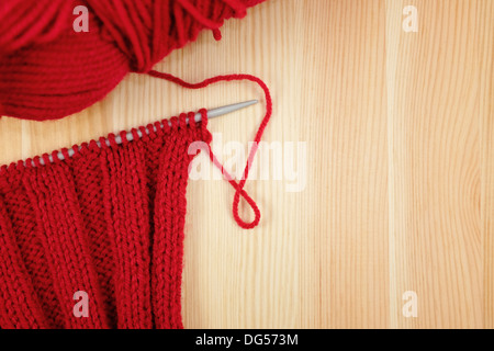 La nervure rouge croix sur l'aiguille à tricoter avec une balle de laine, sur bois Banque D'Images
