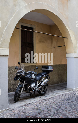 Moto touring BMW Noire stationnée sur une rue propre vide en Italie à l'abri sous une arche. Banque D'Images